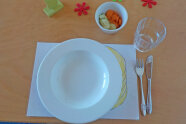 Leerer Teller auf Tisch, daneben Besteck und Glas