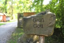 Schild im Wald mit der Aufschrift "Grüß Gott"