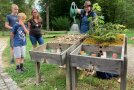 Kindern und Erwachsenen wird ein Model zum Thema Wasserspeicherung Wald und Gebirge gezeigt 