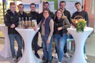 Eine Gruppe junger Menschen stehen hinter einem Stehtisch