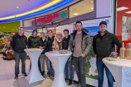 Eine Gruppe junger Menschen stehen hinter einem Stehtisch