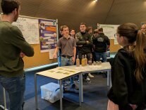Junge Frauen und Männer stehen vor einer Korkwand