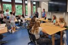 Personen an Tischen in einem Klassenzimmer