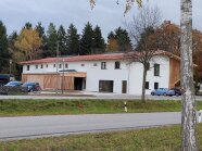 Flaches Gebäude mit Parkplatz davor