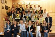 Viele Menschen sitzen auf einer Treppe und halten eine Sonnenblume hoch