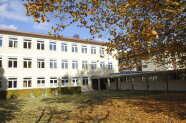 Zweistöckiges Schulgebäude mit Bäumen in Vordergrund