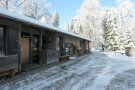 Hauptgebäude des Walderlebniszentrums mit gepflastertem Vorhof im Winter mit Schnee
