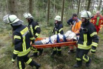 Feuerwehrmänner tragen eine Bahre aus dem Wald