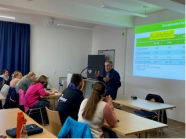 Mehrere Personen sitzen in einem Raum und schauen an die Tafel